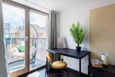 a room with a desk and a balcony with a window at 2-level apartments on Krizikova near the metro in Prague