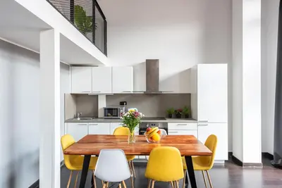 a dining room with a wooden table and yellow chairs at 2-level apartments on Krizikova near the metro in Prague