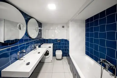a blue tiled bathroom with a sink and a washing machine at 2-level apartments on Krizikova near the metro in Prague