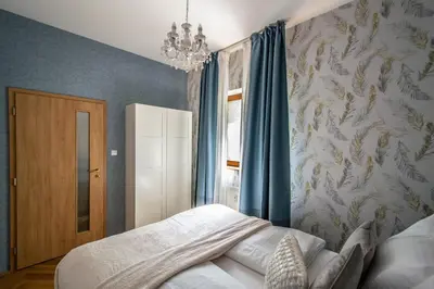 a bedroom with a bed with blue curtains and a chandelier at National Museum 3BDR Golden Stork Spot in Prague