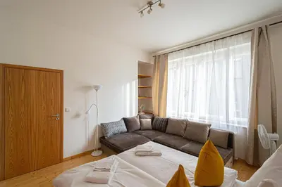 a living room with a couch and a large window at Bright Ruterra Apartment in the Heart of Prague in Prague