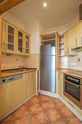 a kitchen with wooden cabinets and a stainless steel refrigerator at Bright Ruterra Apartment in the Heart of Prague in Prague
