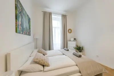 a large bed in a white room with a window at 2BDR Pretty Apartment in the Local Area of Prague in Prague
