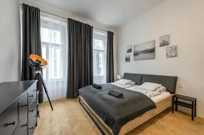a bedroom with a bed and a tv and windows at 2BDR Pretty Apartment in the Local Area of Prague in Prague