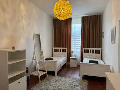 a bedroom with two beds and a yellow chandelier at 2BDR Pretty Apartment in the Local Area of Prague in Prague