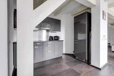 a kitchen with white cabinets and a black refrigerator at Spacious stylish attic in the heart of the center - Karlovo in Prague