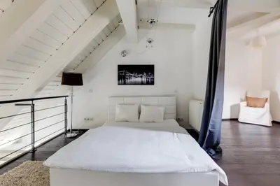 a white bedroom with a bed and a chair at Spacious stylish attic in the heart of the center - Karlovo in Prague