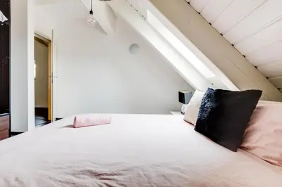 a bedroom with a large white bed with a black pillow at Spacious stylish attic in the heart of the center - Karlovo in Prague