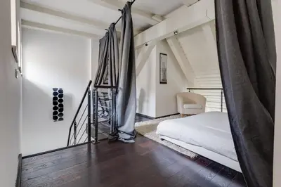 an attic bedroom with a bed and a staircase at Spacious stylish attic in the heart of the center - Karlovo in Prague