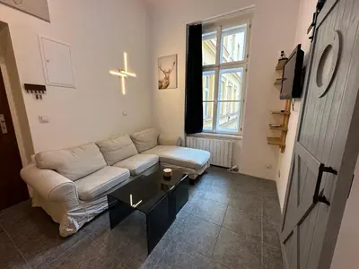 a living room with a couch and a cross on the wall at Cozy New Loft Apartment in Prague