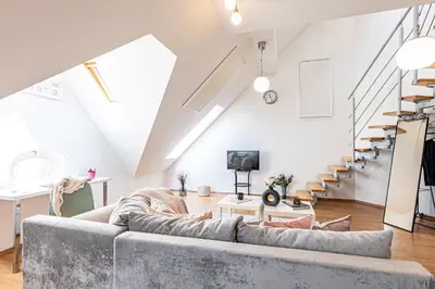 a living room with a couch and stairs at Prague Days - Airy Duplex with Terrace and AC in Prague