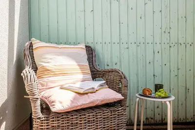 a wicker chair with a book and a side table at Prague Days - Airy Duplex with Terrace and AC in Prague