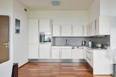 a kitchen with white cabinets and a wooden floor at Spacious Condo in Nusle by Prague Days in Prague