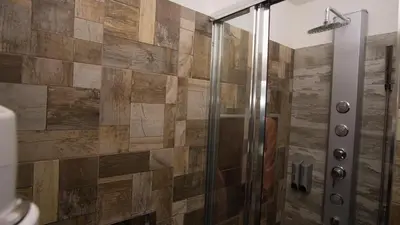 a bathroom with a shower with a wooden wall at Apartment CONTINENTS nearby Main Train and Bus Station in Prague