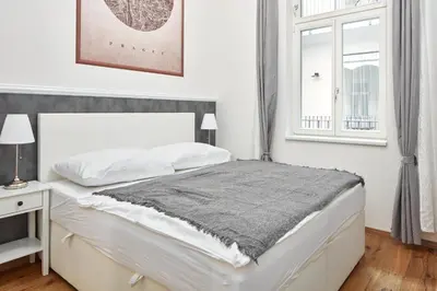 a white bedroom with a bed and a window at Prague Days - One-bedroom Apartment with Workspace by Vltava River in Smíchov in Prague