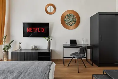 a bedroom with a bed and a desk and a television at Prague Days - Sunlit 1BDR Apartments w Netflix in New Town in Prague