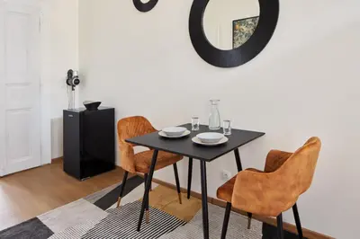 a dining room table with chairs and a mirror at Prague Days - Sunlit 1BDR Apartments w Netflix in New Town in Prague