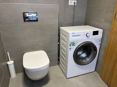 a bathroom with a washing machine and a toilet at Apartman Holesovice,balkon,garaz in Prague