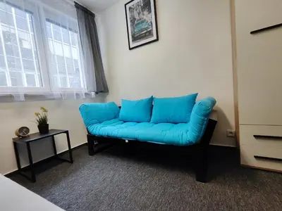a blue couch in a living room with a window at Vibe House Prague in Prague