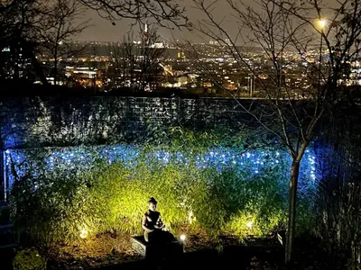 a person sitting on a bench in front of a wall with lights at Romantic stay overlooking Prague in Prague