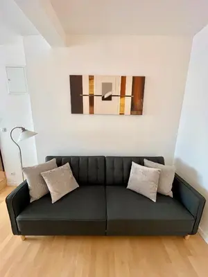a black couch in a living room with a painting at Rezidence Kbely - Free Parking in Prague