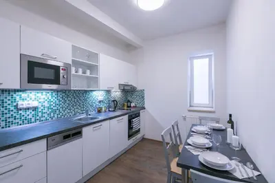 a kitchen with white cabinets and a table with chairs at Cozy apartment in quiet courtyard near Charles Bridge in Prague