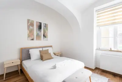 a white bedroom with a bed and a window at George Apartment in Prague