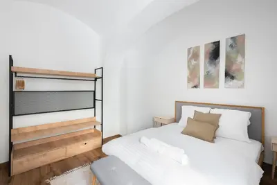 a bedroom with a white bed and a bench at George Apartment in Prague