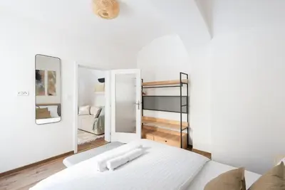 a white room with a bed and a mirror at George Apartment in Prague