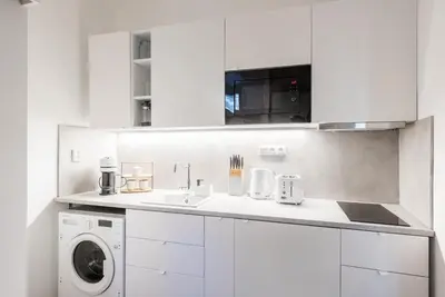 a white kitchen with a sink and a washing machine at George Apartment in Prague