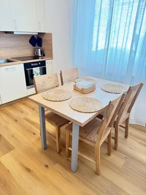 a dining room table with chairs and a kitchen at Parkside Apartments Prague in Prague