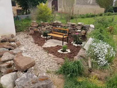 a bench in a garden with rocks and flowers at Zelený grunt in Dřínov