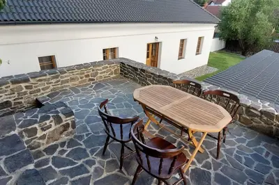 a patio with a table and chairs and a stone wall at degustační dům in Babice