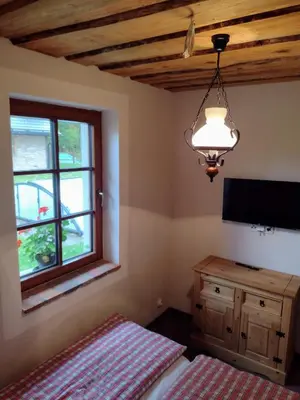 a bedroom with a bed and a tv and a window at Hájovna Libice in Rybníky