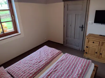 a bedroom with two beds and a window and a door at Hájovna Libice in Rybníky