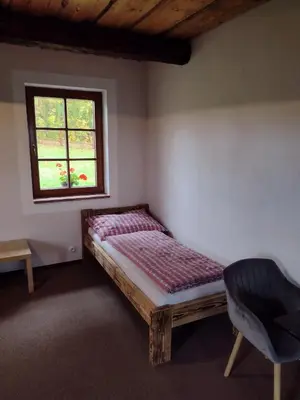 a bed in a room with a window and a chair at Hájovna Libice in Rybníky