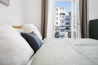 a bed with white pillows and a window with a view at Prague Days - One-bedroom Apartment with Netflix and Balcony in Vinohrady in Prague