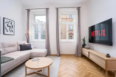 a living room with a white couch and a tv at Prague Days - One-bedroom Apartment with Netflix and Balcony in Vinohrady in Prague