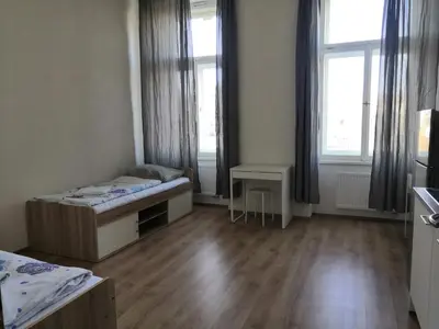 a room with two beds and a table and windows at Brand New Apartments in Prague