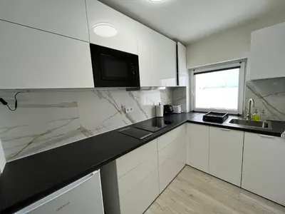 a kitchen with white cabinets and a black counter top at Apartment Golden Prague 78 in Vestec