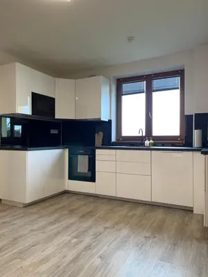 an empty kitchen with white cabinets and a wooden floor at Apartment Golden Prague 78 in Vestec