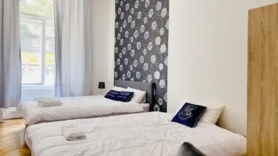 a bedroom with two beds and a wall with a window at Hotel Apartment in square praha 2 in Prague
