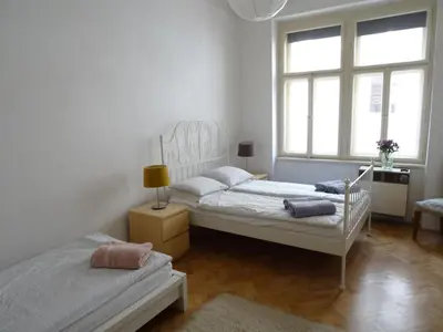 two beds in a white room with two windows at Garden Apartment on Art Nouveau Street in Central Prague in Prague