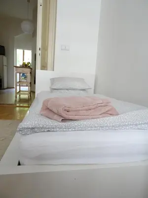 a white bed with a pink blanket on it at Garden Apartment on Art Nouveau Street in Central Prague in Prague