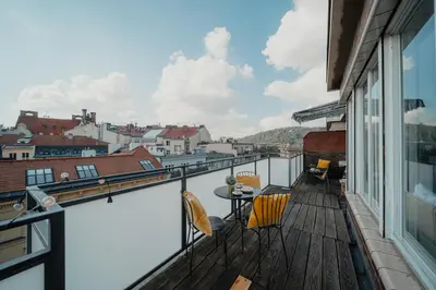 a balcony with a table and chairs on a building at Waterfront River Side Roof Top Apartment - Terrace with city view in Prague