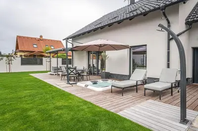a patio with a hot tub and chairs and an umbrella at ESCAPE THE ORDINARY (Sauna & Jacuzzi) in Jesenice