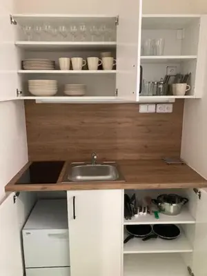 a small kitchen with a sink and white cabinets at Capsule hostel Andel Centre SPIRIT in Prague