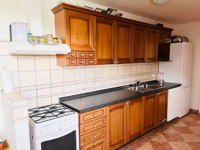 a kitchen with wooden cabinets and a white stove top oven at Apartmán se zahradou 20 minut do centra Prahy in Ořech