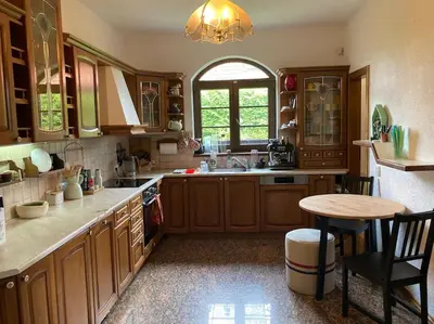 a kitchen with wooden cabinets and a table in it at Spacious villa with an outdoor pool in Černošice in Černošice