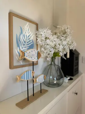 three wooden fish on a shelf next to a vase at Apartmán Květinová zahrada in Prague
